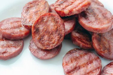 Beyaz bir tabakta sosis dilimleri. Piknik. Yağlı et, yarı bitmiş ürünlerin hazırlanması. Yatay resim.