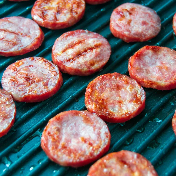 grilled sausage slices. sausages on a grill pan. picnic. fat meat. Preparation of semi-finished products. Square image.