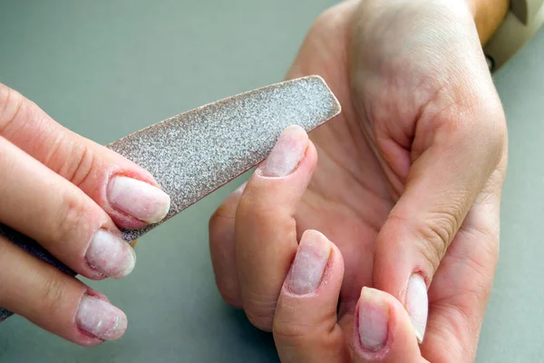 Nail sawing process. Cutting gel nail polish from. Female manicure close up