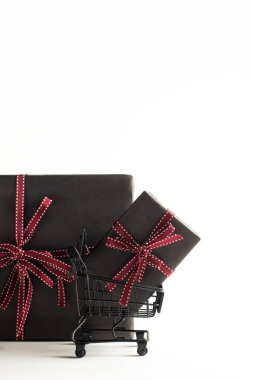 Beyaz arka planda hediye kutuları ve fotokopi alanı olan oyuncak alışveriş arabası. Kara Cuma afişi, alışveriş konsepti. Satış fikri..