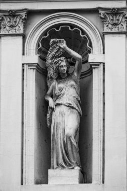 heykeli olan eski binanın siyah beyaz fotoğrafı. 