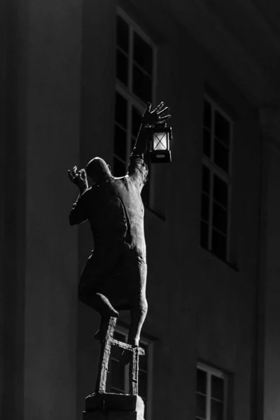 male sculpture and street light in the urban environment, black and white