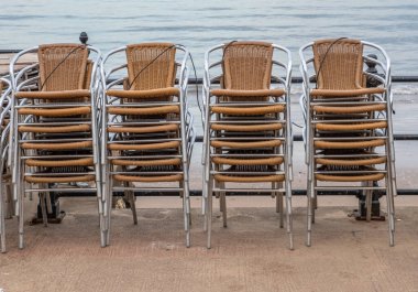 16 Haziran 2022 Scarborough, Kuzey Yorkshire, İngiltere - metal bir korkuluğa bağlanmış rattan sandalyeler.