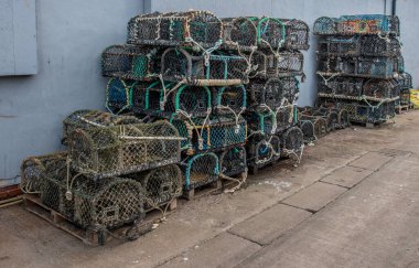 16 Haziran 2022 Scarborough, Kuzey Yorkshire, İngiltere - İskele tarafında gri bir duvara dayalı ıstakoz kapları.