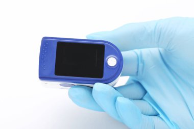 Nabız oksimetresi beyaz arka planda eldivenle doktor elinde.