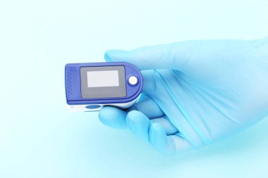 Nabız oksimetresi doktor elinde mavi arka planda eldivenle