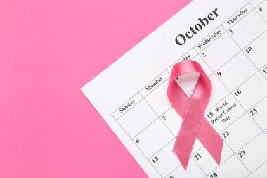 Kanser konsepti. Pembe arkaplanda beyaz kağıt takvimi olan kurdele