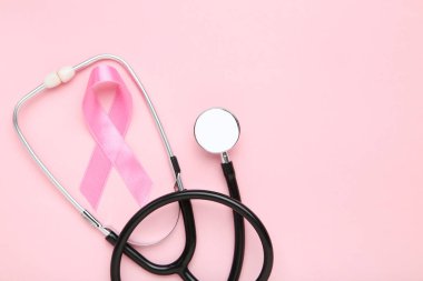 Kanser konsepti. Pembe arka planda kurdele ve steteskop