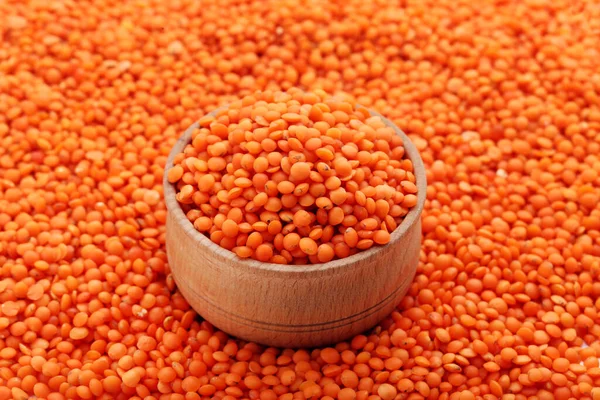 Background of red lentils with wooden bowl