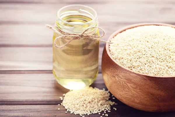 Tahta arka planda susam yağı ve tohumlar