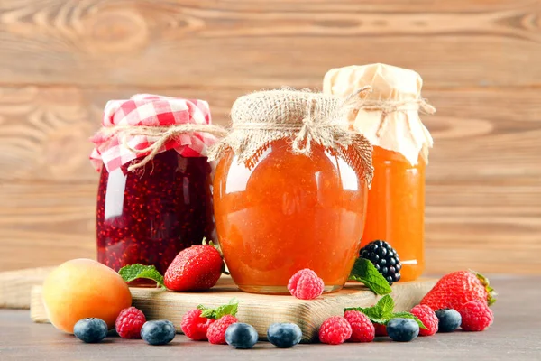 玻璃瓶中的甜果酱 带有成熟的浆果 放在褐色的木桌上 — 图库照片