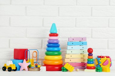 Beyaz tuğla duvar arkasında çeşitli çocuk oyuncakları