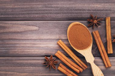 Çubuklu tarçın tozu ve kahverengi ahşap zemin üzerinde yıldız anises