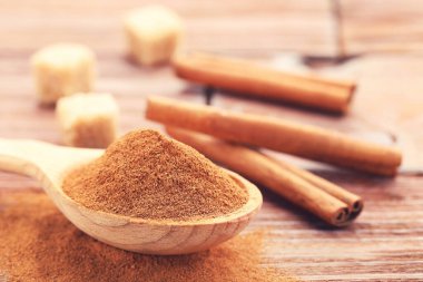 Tarçın tozu, çubuk ve şeker kahverengi ahşap arka planda