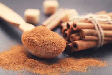 Çubuklu tarçın tozu ve siyah zemin üzerinde şeker