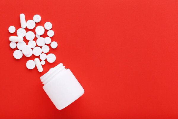 Medicine pills and bottle on red background