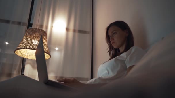 Vrouw werken 's nachts in haar slaapkamer met behulp van laptop computer liggend op het bed — Stockvideo