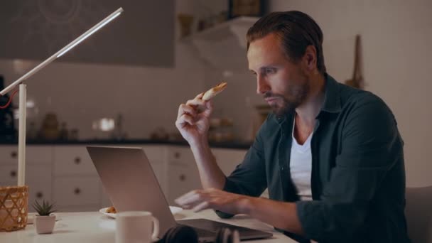 Geceleri evde çalışan, pizza yiyen ve dizüstü bilgisayarda yazan bir adam. — Stok video