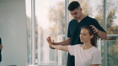 Profesyonel erkek kayropraktik uzmanı, rehabilitasyon merkezinde kadın hasta tedavi eden fizyoterapist.