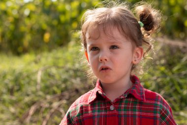 Kırmızı ekose gömlekli güzel sarışın kıvırcık kız. Bulanık yeşil arka planda.