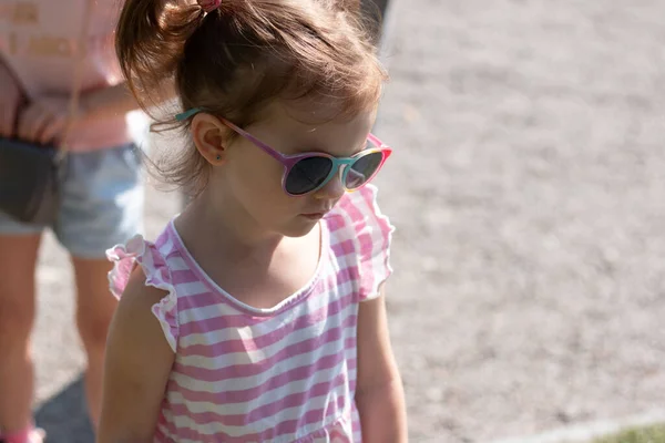 Kleines Trauriges Schönes Mädchen Mit Sonnenbrille Und Zöpfen Auf Einem — Stockfoto
