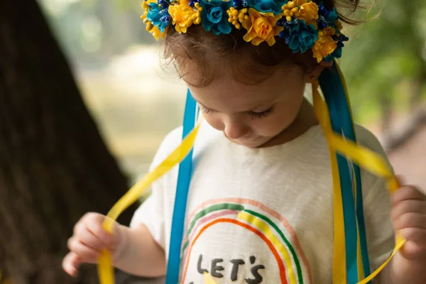头上挂着乌克兰民俗装饰品的可悲女孩 小孩子站在户外摸花环带 — 图库照片