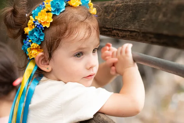 一个穿着乌克兰民族服装装饰辫子的小孩从长椅上看过去 — 图库照片