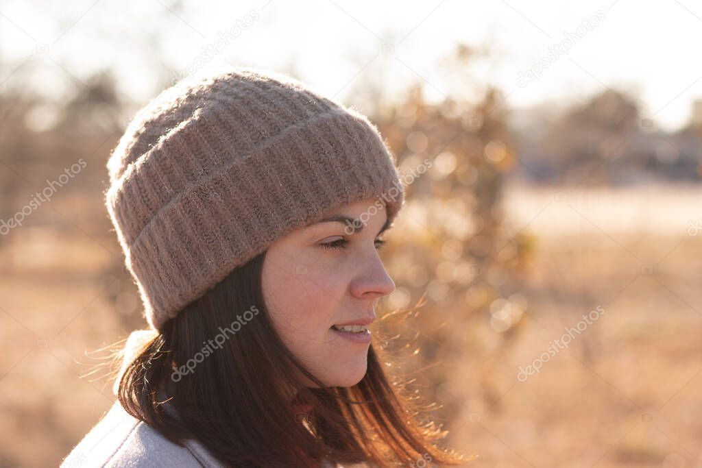 Smiling girl in a knitted hat and coat stands against the background of the autumn desert lake landscape