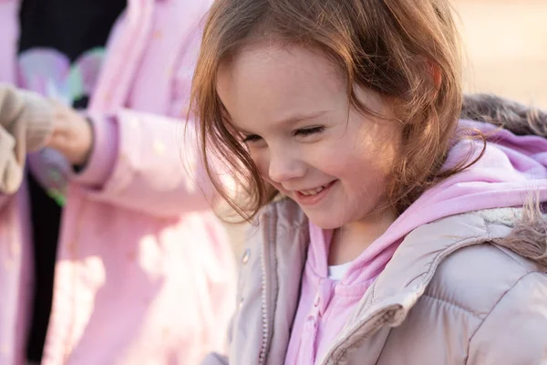 Bulanık şehir manzarasında duran, uzun saçlı, güzel, gülümseyen, sıcak elbiseli kızıl saçlı bir çocuğun yakın plan portresi.