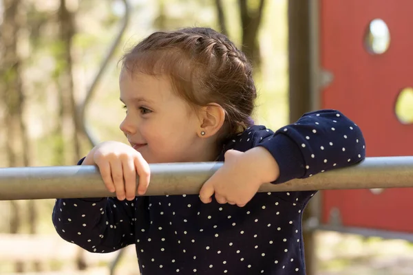 Gyönyörű Kislány Vigyorog Oldalra Néz Felmászik Csövön Játszótéren — Stock Fotó