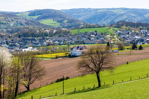 Çevresinde tarlalar, arkasında dağlar olan bir kır evinin manzara fotoğrafı.