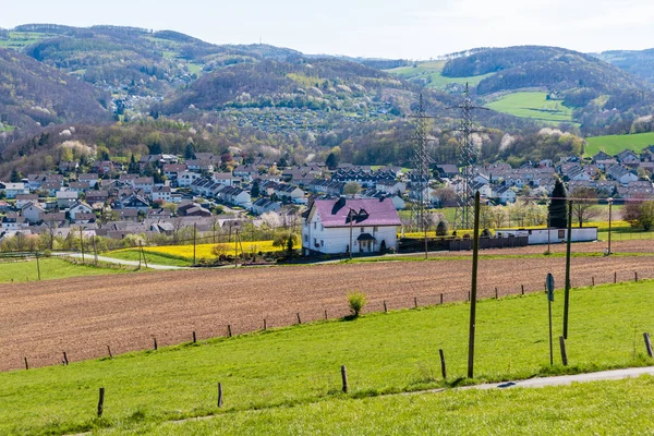 Çevresinde tarlalar, arkasında dağlar olan bir kır evinin manzara fotoğrafı.