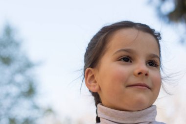 Gri balıkçı yaka kazaklı, birinci sınıf güzel bir kızın mavi gökyüzüne yakın portresi.