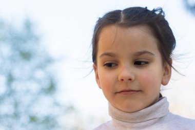 Gri balıkçı yaka kazaklı, birinci sınıf güzel bir kızın mavi gökyüzüne yakın portresi.