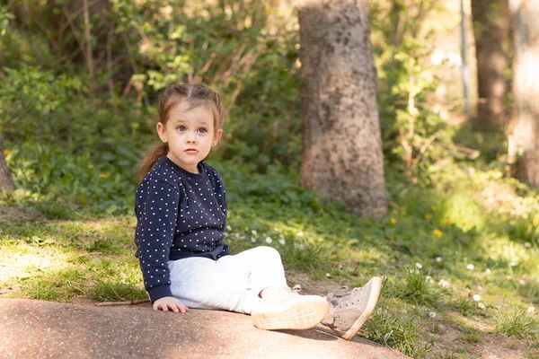 Little Beautiful Girl Sits Stone Surface Park Blurred Green Natural — Stock Fotó