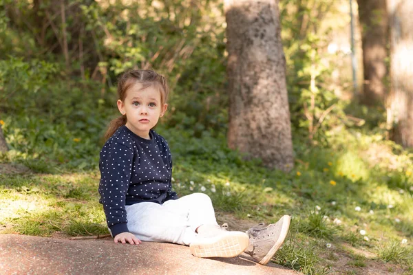Little Beautiful Girl Sits Stone Surface Park Blurred Green Natural — Stock Fotó