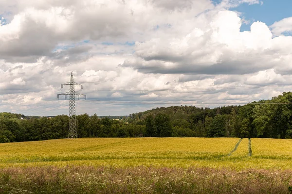 緑のエネルギー風景写真 黄色のドイツのフィールドの真ん中に高電圧タワー — ストック写真