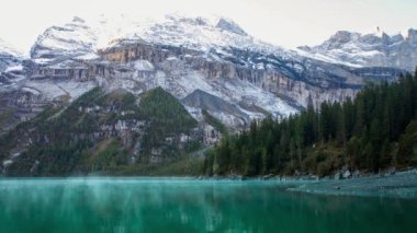 Mavi bir gölette hızlı hareket eden balıkçı tekneleri. İsviçre, Kandersteg yakınlarındaki İsviçre Alplerinde Oeschinen Gölü 'nün güneş ışınlarıyla sabah 4' te.. 