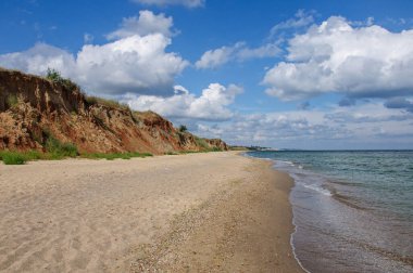 A beautiful seascape with a steep high red clay shore and a beautiful sky