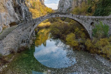 Kokori 'nin sonbahar mevsiminde Zagori, Epirus Yunanistan' daki Voidomatis nehrinde yer alan eski kemer taşı köprüsü (Noutsos).