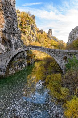 Kokori 'nin sonbahar mevsiminde Zagori, Epirus Yunanistan' daki Voidomatis nehrinde yer alan eski kemer taşı köprüsü (Noutsos).