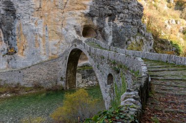 Kokori 'nin sonbahar mevsiminde Zagori, Epirus Yunanistan' daki Voidomatis nehrinde yer alan eski kemer taşı köprüsü (Noutsos).