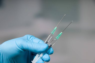 Doktorun elini tıbbî eldivenlerle kapat. Aşı için iki şırınga hazırla.