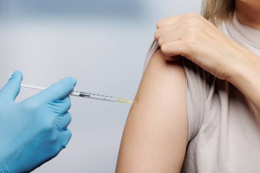 Bir kadının koluna koronavirüs aşısı uygulayan bir doktorun elini kapat. 