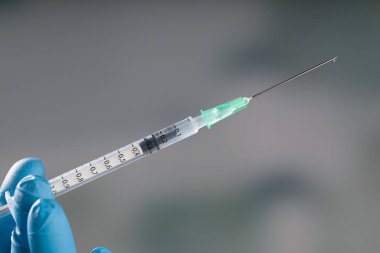 Doktorun elini tıbbî eldivenlerle Coronavirus şırıngası ya da grip aşısı ile kapatın.