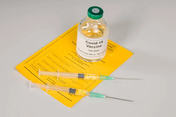 document of international certificates of vaccination and a bottle of covid-19 vaccine with two syringes