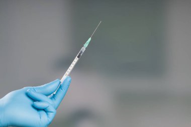 Doktorun elini tıbbî eldivenlerle kapatın. İğne için hazır bir şırınga ile. 