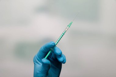 Doktorun elini tıbbî eldivenlerle kapatın. İğne için hazır bir şırınga ile. 