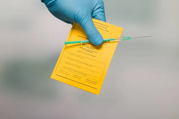 doctor's hand with document of international certificates of vaccination and a syringe