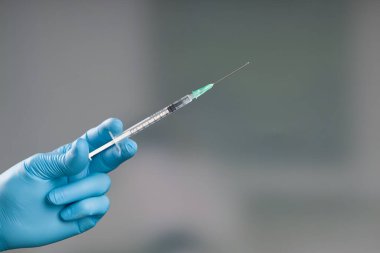 Doktorun elini tıbbî eldivenlerle Coronavirus şırıngası ya da grip aşısı ile kapatın. 